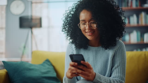 Person happily using a smartphone on a couch, illustrating the importance of mobile apps for business.